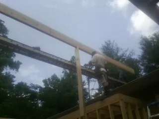 Carpenter setting a ridge beam over a new addition frame — Ice Dam Removal by Roofing Brothers in Lebeau