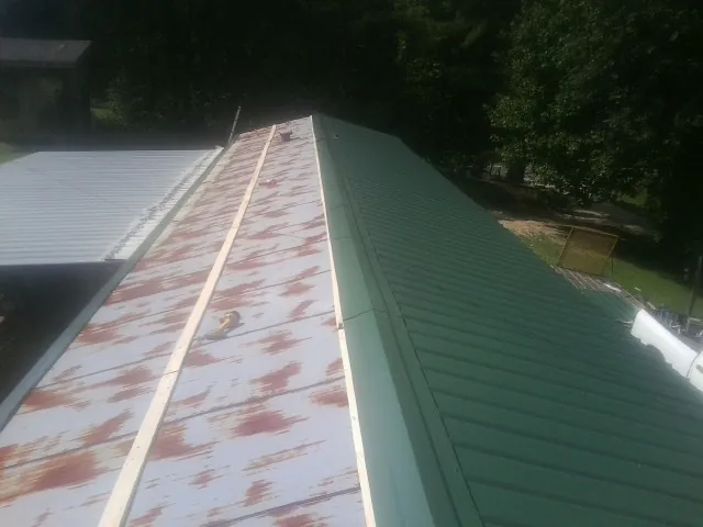 Old rusted panels beside newly installed green metal roofing — Wind Damage Roof Repair by Roofing Brothers in Lebeau