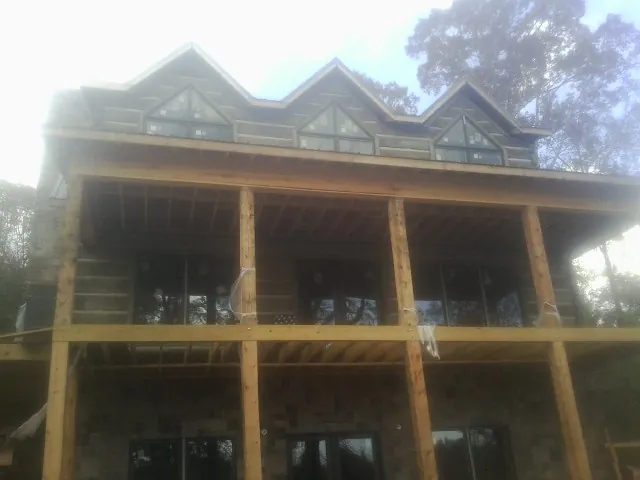 Dormers and porch framing on a large log home under construction — Roof Coating work by our crew in Lebeau