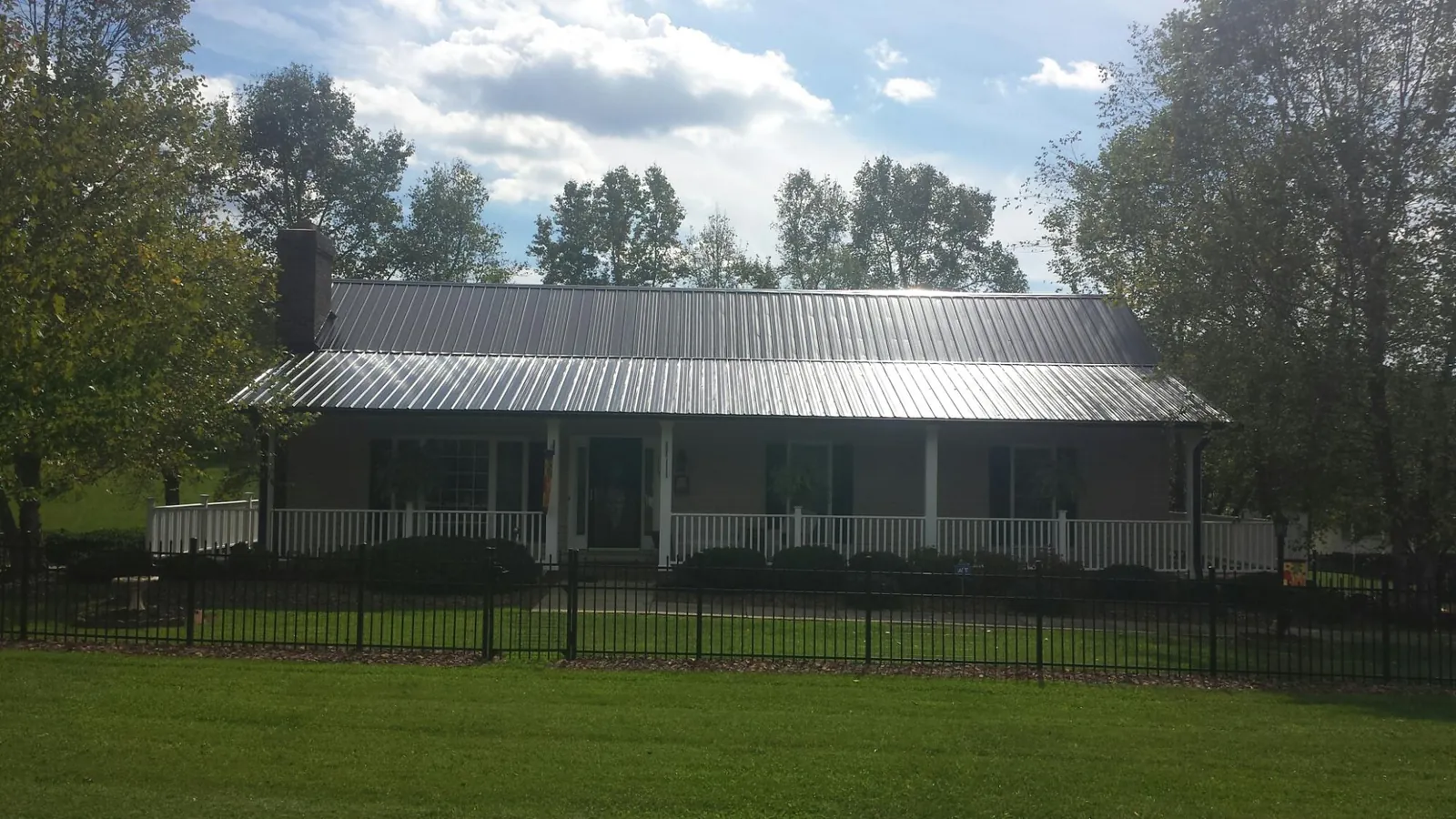 Gray metal roof on a brick ranch with a full width front porch — Gutter Guard Installation work by our crew in Lebeau