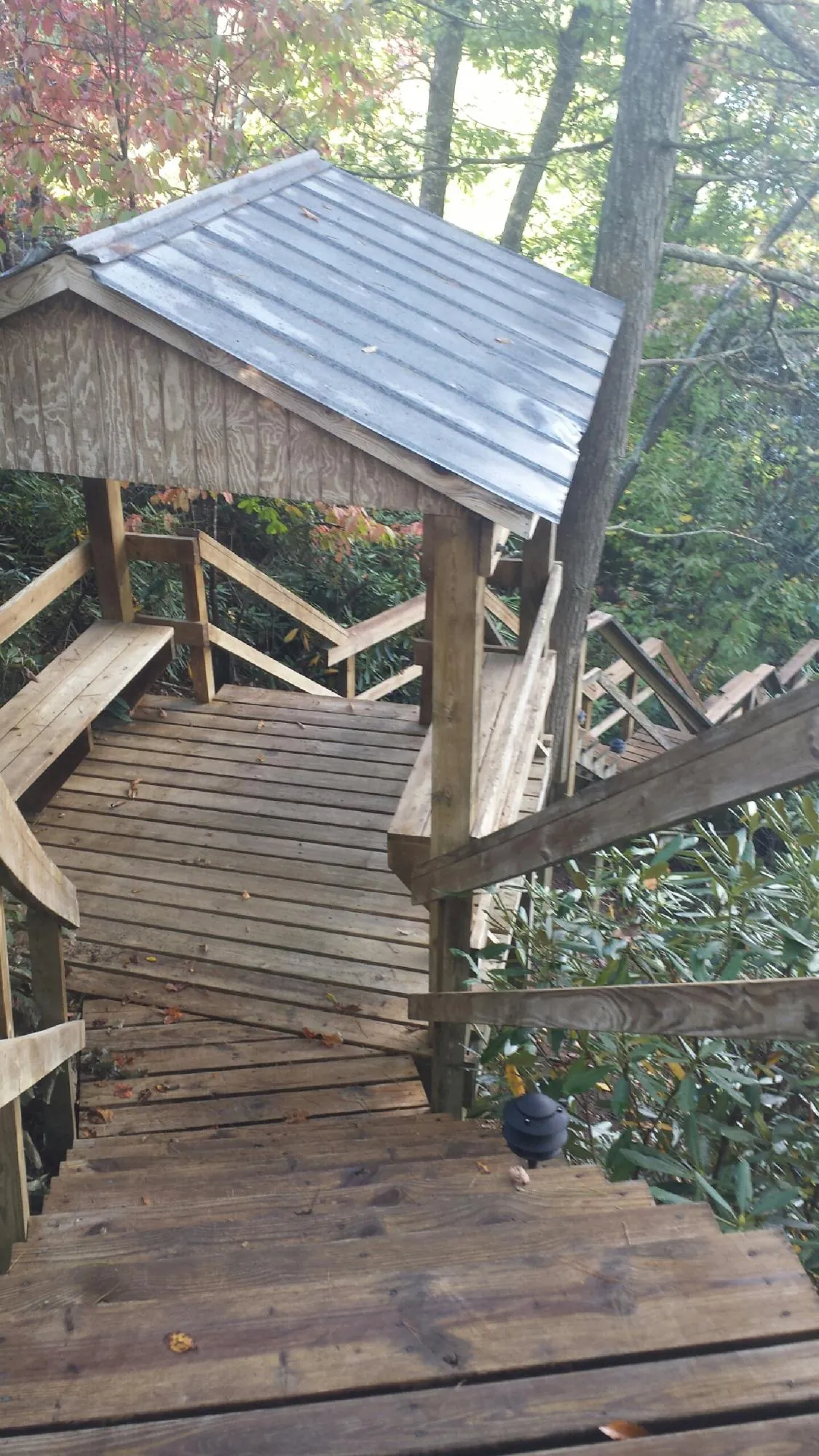 Metal roofed shelter over wooden steps on a wooded walkway — Skylight Repair & Installation work by our crew in Lebeau