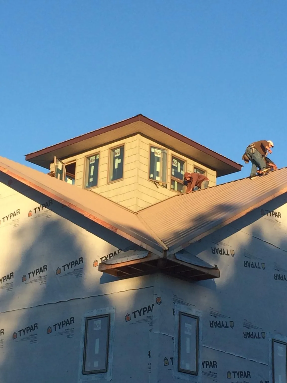Roofers working around a rooftop cupola on a new metal roof at sunset — Roof Waterproofing in Lebeau by Roofing Brothers